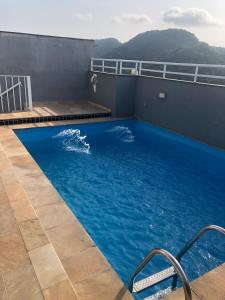 Una gran piscina azul en la parte superior de un edificio en Apartamento Veleiros da Ilha - Praia do Tombo, en Guarujá