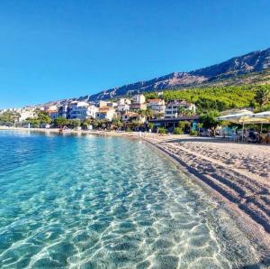 a beach with turquoise water and buildings in the background at Apartman Aria in Dugi Rat