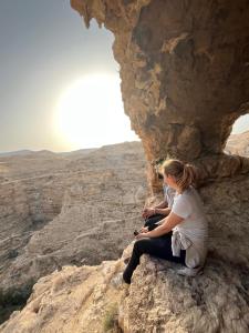 dos personas sentadas en una roca en el desierto en Bethlehem City Hostel, en Bethlehem