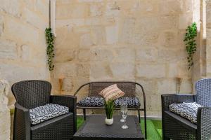 a patio with three chairs and a table with a vase on it at Appartement Jungle - Libourne Centre - 4 pers - Sauna - Netflix in Libourne