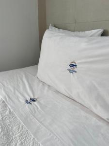 Una cama con sábanas blancas con logotipos. en AZUL ARENA Hotel Boutique en Mazatlán