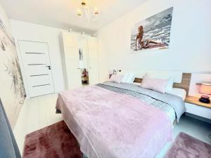 a bedroom with a large bed and a chandelier at Apartament Nadmorski - Plac Unii - Parking in Gdynia