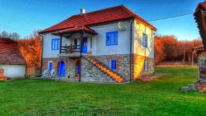 a house with a red roof and blue windows at Domacinstvo Pajovic in Gornji Milanovac