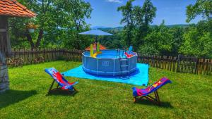 a pool in the yard with two chairs and an umbrella at Domacinstvo Pajovic in Gornji Milanovac