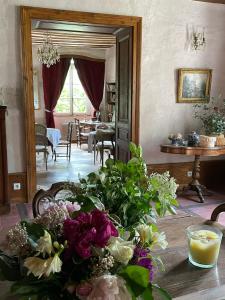 Cette chambre comprend une table avec un bouquet de fleurs. dans l'établissement Domaine du Très-Haut - Château de Montanges, à Montanges