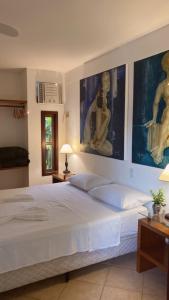 a bedroom with a large white bed with pictures on the wall at Ateliê 22 in Natal