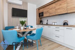 a kitchen with a wooden table and blue chairs at Dom Baltic Home I Horizon Park - Aprent in Dziwnówek