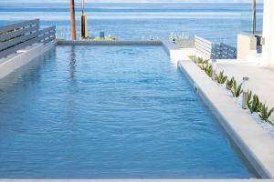 a swimming pool with the ocean in the background at Theros Suites in Dhiminión