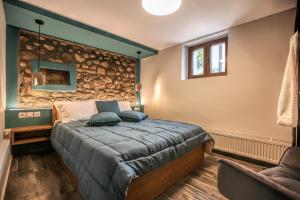 a bedroom with a bed and a stone wall at Avli Luxurious House in Kalabaka