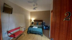 1 dormitorio con 1 cama y 1 silla roja en Recanto dos Ipês Pousada, en Divisa