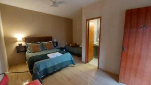 1 dormitorio con 2 camas y puerta a una habitación en Recanto dos Ipês Pousada, en Divisa