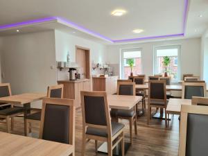 a dining room with wooden tables and chairs at Hotel Pension Nordzeit in Norddeich