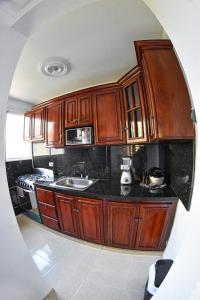 una cocina con armarios de madera y encimeras negras en Apartamento en la carreras próximo al monumento, en Santiago de los Caballeros