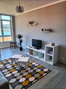 sala de estar con sofá, TV y alfombra en O Vendaval, en Corcubión