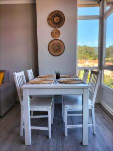 una mesa y sillas blancas en una habitación con ventana en O Vendaval, en Corcubión