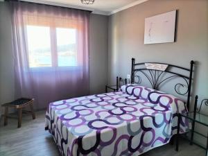 1 dormitorio con 1 cama con edredón morado y blanco en O Vendaval, en Corcubión