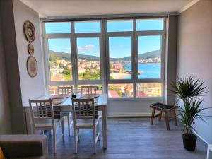 a dining room with a table and chairs and a large window at O Vendaval in Corcubión