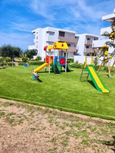 a playground with slides on a green lawn at LUNJApartment in Imi Ouaddar