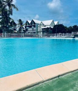 a large blue swimming pool with houses in the background at Studio le Colibri, Entre terre et mer, vue incroyable, citerne in Le Gosier +6 photos