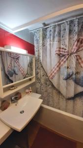 a bathroom with a sink and a shower curtain at Au Doubs Refuge in Métabief