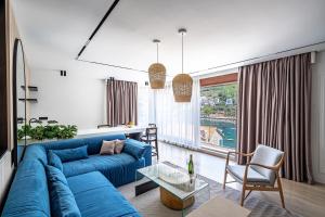a living room with a blue couch and a large window at Blanche Cliff Apartments in Sveti Stefan