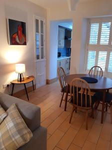 ein Wohnzimmer mit einem Tisch und Stühlen sowie eine Küche in der Unterkunft Sanderling - Grade 2 Listed Georgian Townhouse by the sea in Penzance