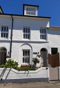 ein weißes Haus mit einer Bank davor in der Unterkunft Sanderling - Grade 2 Listed Georgian Townhouse by the sea in Penzance