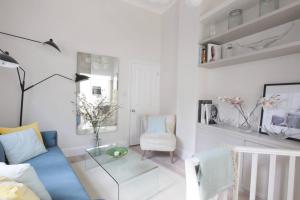 ein Wohnzimmer mit einem blauen Sofa und einem Glastisch in der Unterkunft Newly Refurbished 1 Bedroom in Vibrant Notting Hill in London