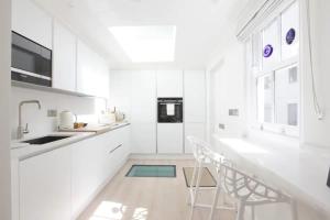 eine weiße Küche mit einem Waschbecken und einem Tisch in der Unterkunft Newly Refurbished 1 Bedroom in Vibrant Notting Hill in London