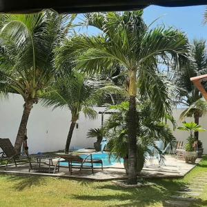 a resort with palm trees and a swimming pool at HOSPEDARIA CONSULADO PAULISTA in Taíba