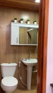une salle de bain avec toilettes, lavabo et miroir dans l'établissement Melhores Suítes, à Arraial do Cabo
