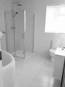 uma casa de banho branca com um chuveiro e um WC. em Annie's House with Thermal Health Spa em Moville