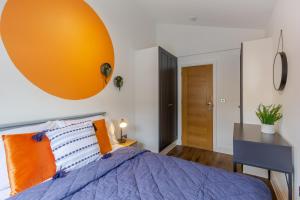 a bedroom with a bed with an orange pillow and a desk at Bright cheery 4 bd apartment by Brighton Station in Brighton & Hove