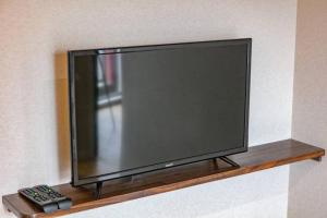 a flat screen tv on a shelf with a remote control at Early Arc Osaka in Osaka