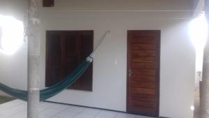 a hammock hanging from the side of a building with two doors at Uma casa para descansar em um cenário paradisíaco. in Icapuí