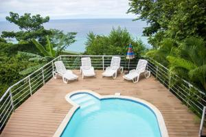 a deck with a swimming pool and chairs and the ocean at Sunshine Sanctuary Boutique Jungle Lodge in Montezuma