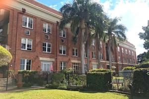 a large brick building with palm trees in front of it at Spacious 1 Bedroom Apartment in Teneriffe Brisbane in Brisbane