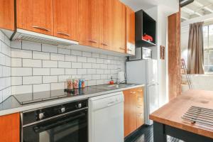 a kitchen with wooden cabinets and a black dishwasher at Spacious 1 Bedroom Apartment in Teneriffe Brisbane in Brisbane