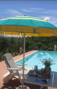 una silla y una sombrilla junto a la piscina en La Vecchia Quercia, en Pergine Valdarno