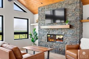 a living room with a stone fireplace with a tv at Luxury Living at The Eagles Perch Palmer AK in Palmer