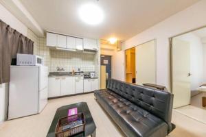 Una sala de estar con un sofá y una cocina. en Ash Court Joto, en Osaka