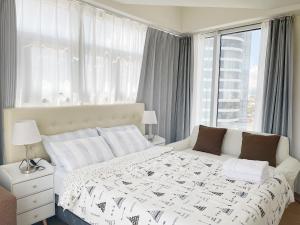 a bedroom with a white bed and a large window at Inspiria in Davao City