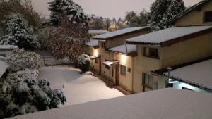 un patio cubierto de nieve con una casa y árboles en Casa Campo B&B en San Carlos de Bariloche