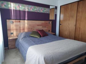 une chambre avec un grand lit avec une tête de lit en bois dans l'établissement Casa Campo B&B, à San Carlos de Bariloche