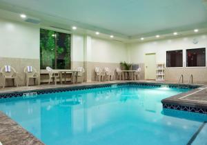 a swimming pool with a pool table and chairs at Holiday Inn Express Hotel and Suites Akron South-Airport Area, an IHG Hotel in Akron