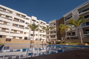 ein großes Apartmenthaus mit Palmen und einem Pool in der Unterkunft Blu paradise,a ray of sunshine between sea & pool in Agadir