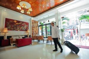 un hombre está tirando de una maleta en una habitación en Diamond Nostalgia Hotel & Spa, en Hanói