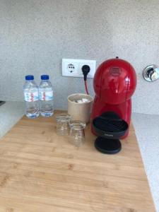 a red coffee maker on a wooden counter with water bottles at T0 no centro do Porto in Porto