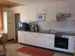 a kitchen with white cabinets and a microwave at Ferienwohnungen Pötscher Maria in Matrei in Osttirol