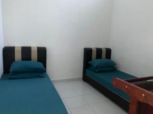two beds sitting next to each other in a room at SRI KENANGA HOMESTAY in Bandar Penawar +1 photo